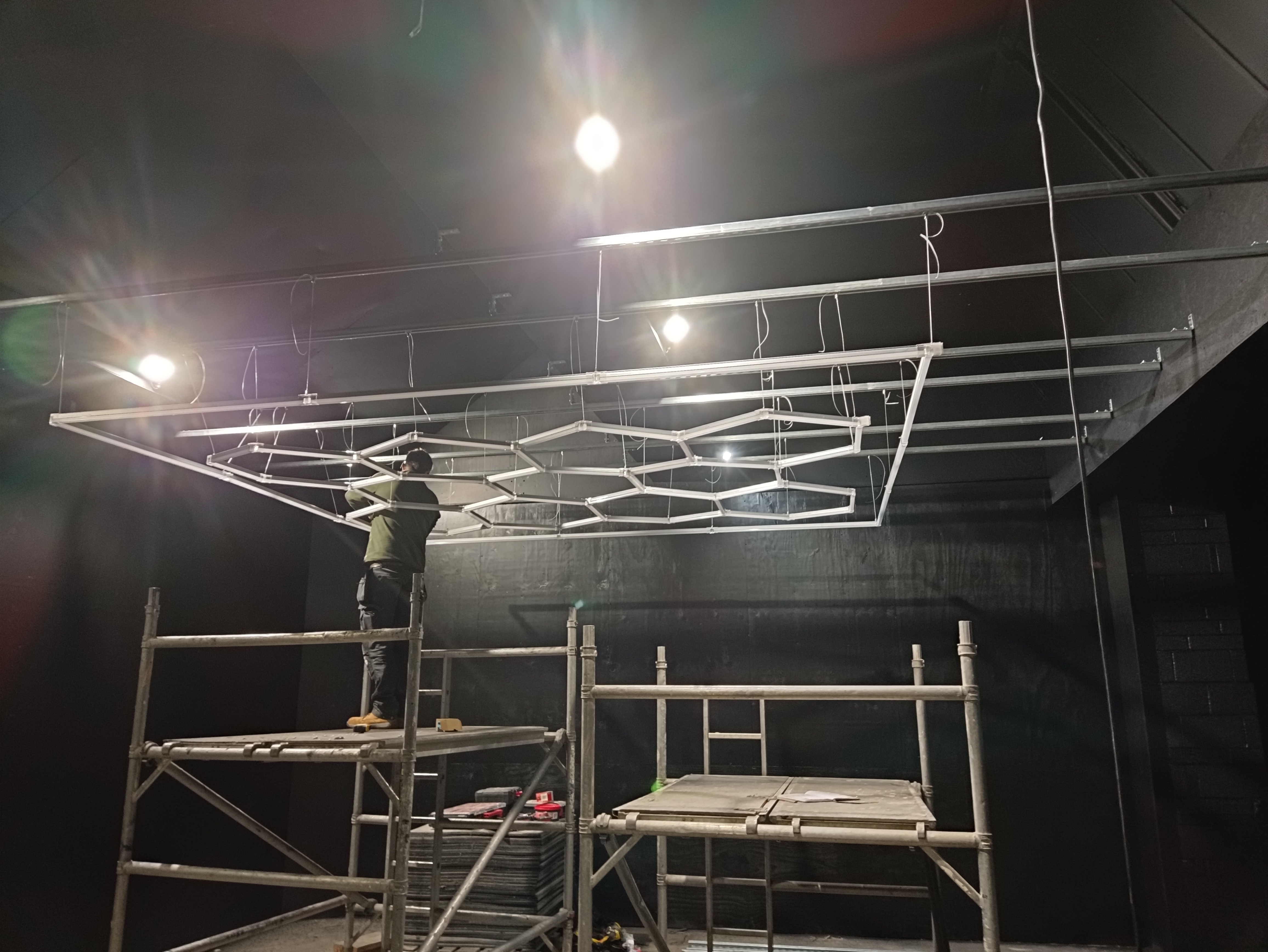 Hexagonal LED lighting sections being assembled during a commercial gym installation
